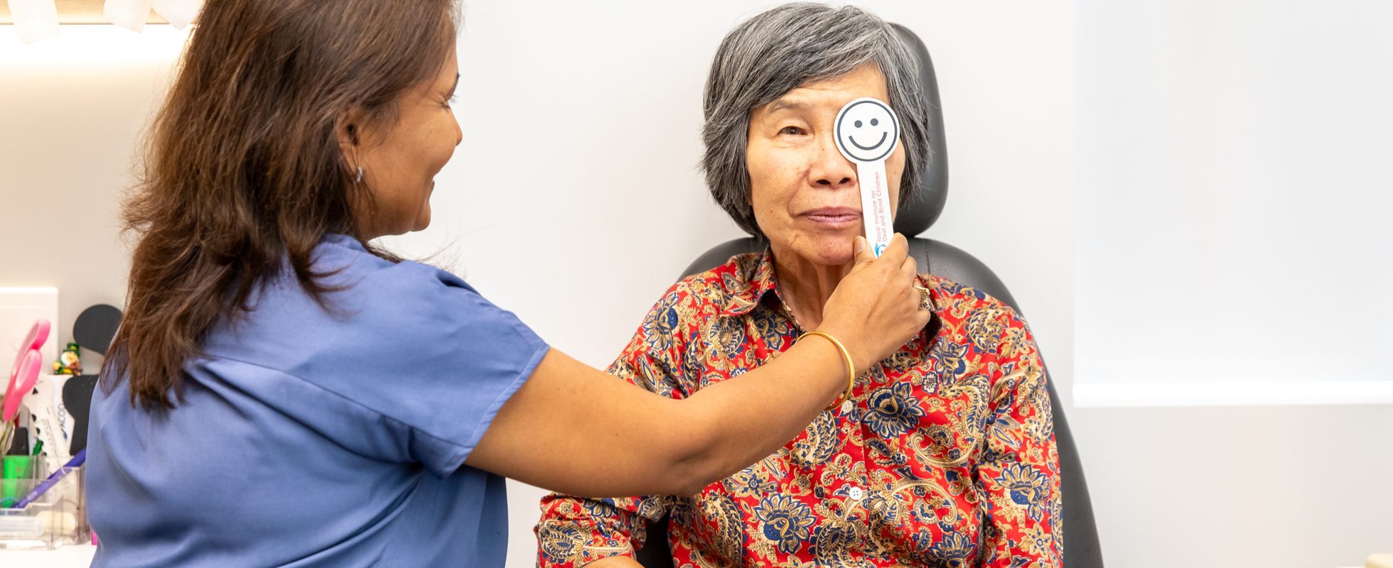 Eastwood Eye Surgery clinician holding an occluder over a patient's eye during a visual acuity test at a cataract consultation