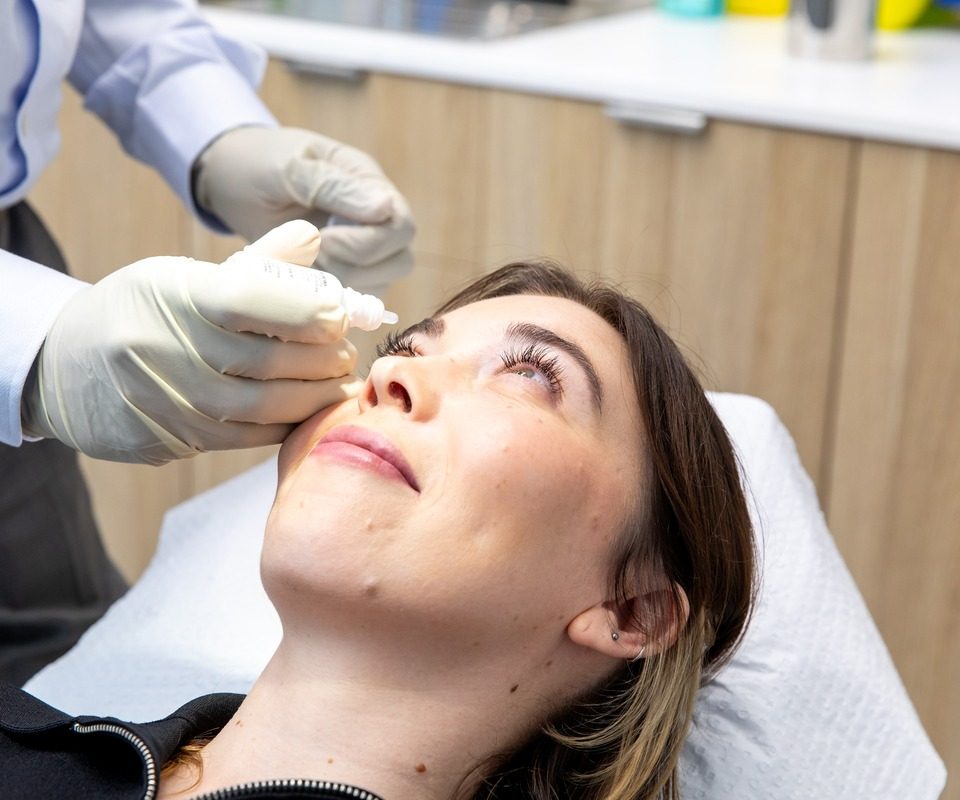 Ophthalmologist wearing gloves retracting a patient's lower eyelid to instil drops before an eyelid procedure at Eastwood Eye Surgery
