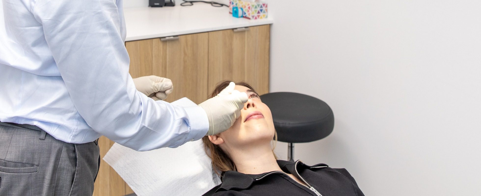 Ophthalmologist examining a patient's upper eyelid in the treatment room at Eastwood Eye Surgery