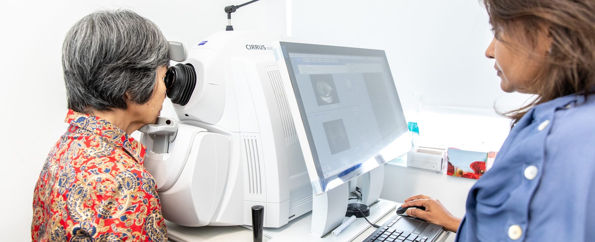 Eastwood Eye Surgery clinician capturing an optical coherence tomography scan of a patient's retina, the scan visible on the monitor